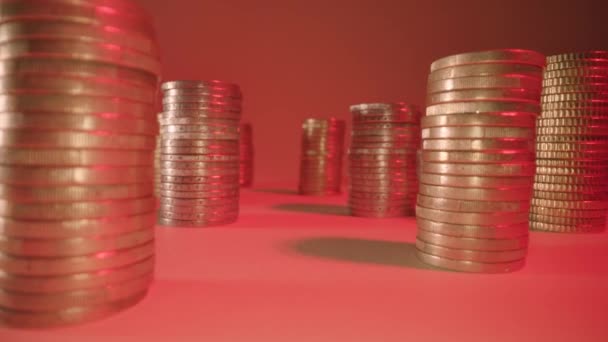 Beweging tussen stapels munten op tafel bij zacht rood licht — Stockvideo