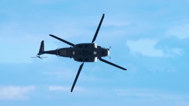 Bulutlu gökyüzüne doğru uçan büyük helikopter silueti.