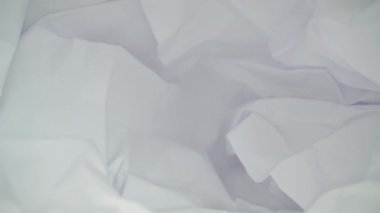 Karanlık stüdyoda, siyah masanın üzerine buruşmuş beyaz bir sayfa kağıt.