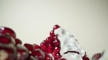 Motion above pieces of pomegranate fruit on light background