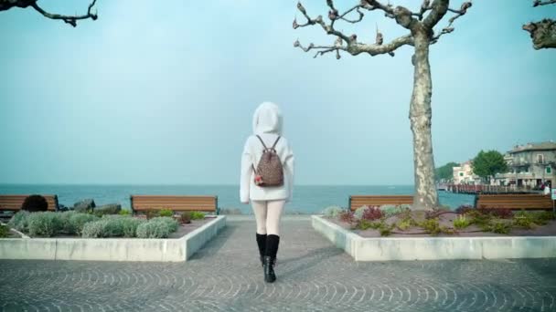 Kvinnen går på fyllingen og kommer nærmere Garda-sjøen. – stockvideo