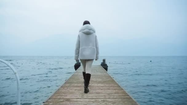 Mulher caminha no cais de madeira desfrutando de vistas do lago Garda — Vídeo de Stock
