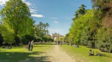 Şehir parkındaki Zafer Kemeri 'nde yeşil çimlerin üzerindeki ağaçların arasında turist kalabalığı vardı. Güneşli bir günde Milano 'daki popüler turizm merkezi