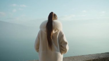 Kadın, Garda Gölü 'ne bakan gözlem güvertesinde sis kaplı dev dağlara karşı duruyor. İtalya 'da tatil yapan bayan turist.