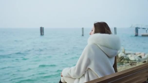 Young Lady White Furry Coat Sits Bench Looking Boats Sailing — Vídeo de Stock