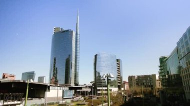 MILAN, İtalya - 10 Nisan 2022: Güneşli bir günde Milano 'da cam yüksek binalar açık mavi gökyüzüne karşı duruyor. İtalya 'da modern mimariye sahip merkez cadde 10 Nisan' da Milano 'da
