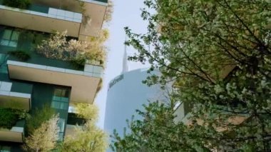 MİLAN, İtalya - 10 Nisan 2022 Milano 'da gökyüzüne karşı dikey orman evinin yakınında yeşeren gür bir ağaç. İtalyan şehrinde sıradışı mimari 10 Nisan 'da Milan' da alçak açılı çekim