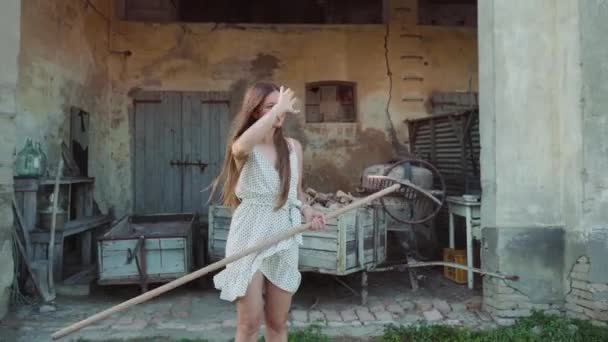 Barefoot Young Woman Holds Rake Walking Grass Old Country Building — Stockvideo