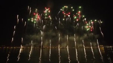 Bright colorful fireworks launched in air bursting simultaneously against dark sky over night city. Traditional ending of Feast of Redeemer celebration