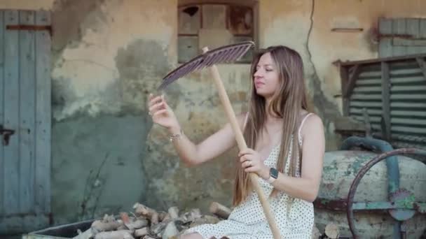 Young Woman Touches Rake Sitting Old Cart Firewood Ruined Building — Stok video