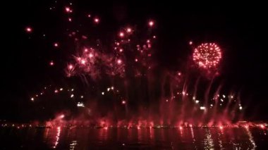 Incredible red fireworks burst and glitter in air above city in late evening. Traditional celebration of Feast of Redeemer in Venice