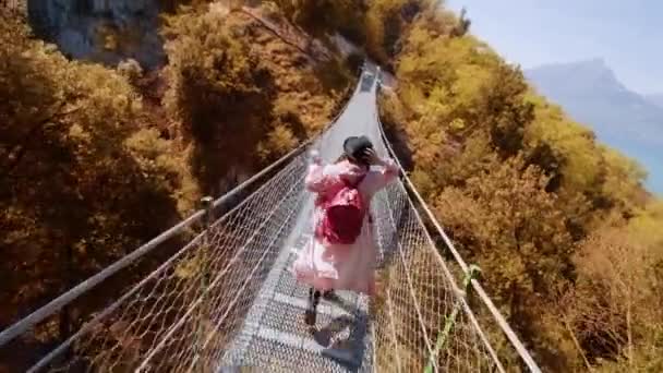 Жінка Біжить Пішохідному Мосту Через Пишні Жовті Дерева Тримаючись Чорну — стокове відео