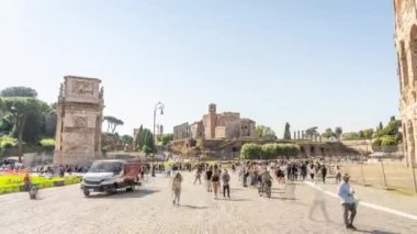 ROME, ITALY - MAY 12 2022: People walk on street sightseeing ancient ruins and structures of Rome on sunny day. Arch of Constantine built near Colosseum hyper lapse on May 12 in Rome