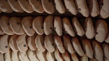 Fresh ham legs hang from ceiling in dark and dry premise illuminated by light. Raw flavored meat hangs to air out and reduce moisture closeup