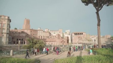 ROME, ITALY - MAY 12 2022: Tourists visit Trajan Forum with ancient ruins in Rome on sunny day. Historical architecture of Italian capital under blue sky on May 12 in Rome