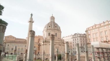 Church of Most Holy Name of Mary and columns at Trajan Forum in Rome under cloudy sky. Ancient ruins and architecture in Italian city
