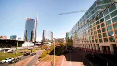 MILAN , ITALY - APRIL 10 2022: Central street with traffic and high-rise buildings in Milan on sunny day in spring. Modern architecture in touristic Italian city on April 10 in Milan