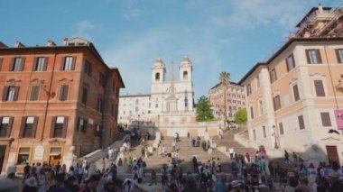ROME, ITALY - MAY 12 2022: Crowded walking street near Spanish Steps and vintage buildings in center of Rome. Historical architecture under blue sky in Italian city on May 12 in Rome