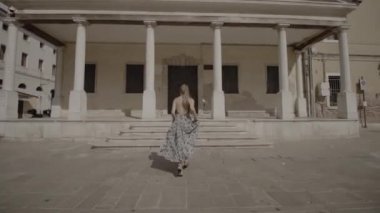 Donna runs and beats with her hand on the closed door of an ancient Venetian building