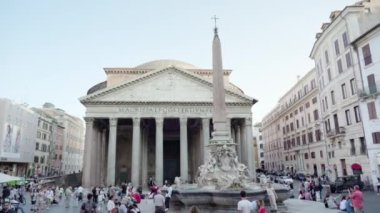 ROME, ITALY - MAY 12 2022: People walk near fountain against Pantheon in Rome on summer day. Ancient building with white columns in center of Italian capital on May 12 in Rome