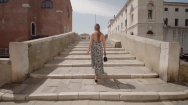 Woman in heels stumbles on the stairs of Venice