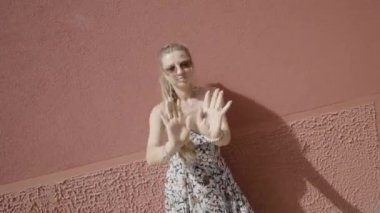 Woman dances in front of the red wall in the sun