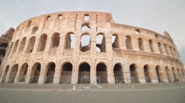 Famous Colosseum built in historical center of Rome on empty square at sunrise on cloudy day. Large ancient amphitheater as major travel destination