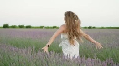 Beautiful young woman runs on the green lavender field in summer