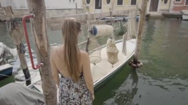 Woman makes gestures in front of boat with fishing nets in Chioggia