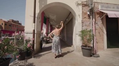 Woman walks dancing funny under Venetian arcades