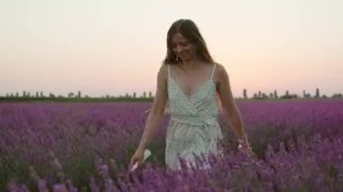 Elinde telefon olan kadın gün batımında lavanta tarlasında koşar.