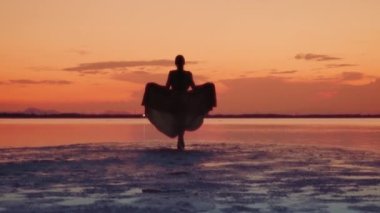 Venedik gölünün güzel gün batımında ıslak sahilde yürüyen genç bir kadının silueti.