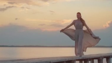 Rüzgarda uçan kadın lagünün üzerinden ahşap geçitten geçiyor.