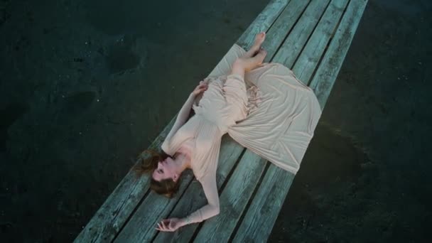 傍晚时分 穿着雅致服装的年轻时尚模特躺在废弃沙滩上的木制码头上 — 图库视频影像