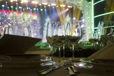 Şarap bardakları masanın üzerinde beyaz bir masa örtüsünün üzerinde. Yeni yıl kutlamalarından önce.