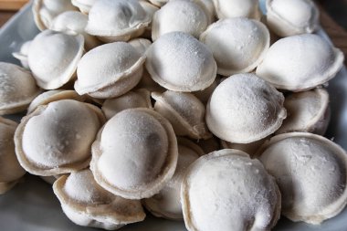 Ev mutfağında hamur tatlısı. Tavada kaynamış hamur köftesi. Arka plan olarak çiğ donmuş hamur köfteleri, üst manzara. Ev yemeği.