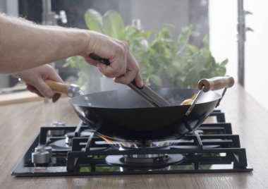 Gaz ocağında kızartma tavası. Şef pişirme işlemini kontrol ediyor. Gaz sobasında pişirme. Avrupa 'da pahalı gaz.