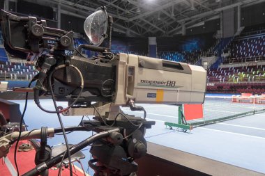 Profesyonel fotoğrafçı video ya da televizyon yayınları için tenis turnuvasındaki etkinlikten önce video kamera kurun ve hazırlayın.