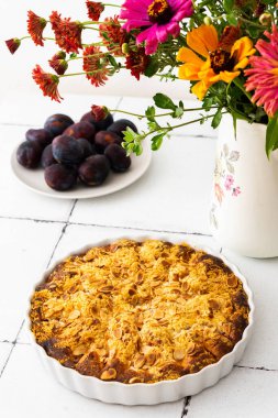 Badem taneli ev yapımı erik keki, vazoda sonbahar çiçekleri.