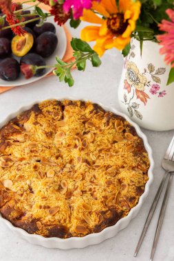 Badem taneli ev yapımı erik keki, vazoda sonbahar çiçekleri.