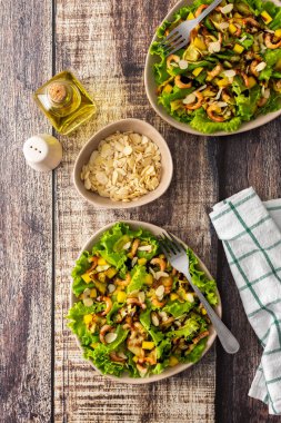 Lezzetli hafif akşam yemeği, kızarmış kabak dilimli marul, mango, karides ve badem yaprağı, bardakta limonlu su.