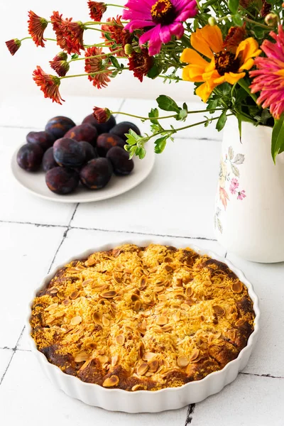 Badem taneli ev yapımı erik keki, vazoda sonbahar çiçekleri.