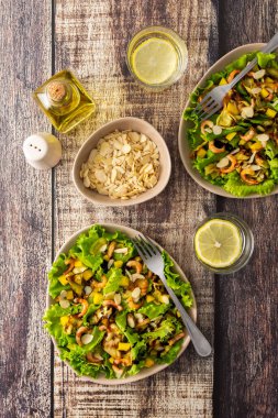 Lezzetli hafif akşam yemeği, kızarmış kabak dilimli marul, mango, karides ve badem yaprağı, bardakta limonlu su.