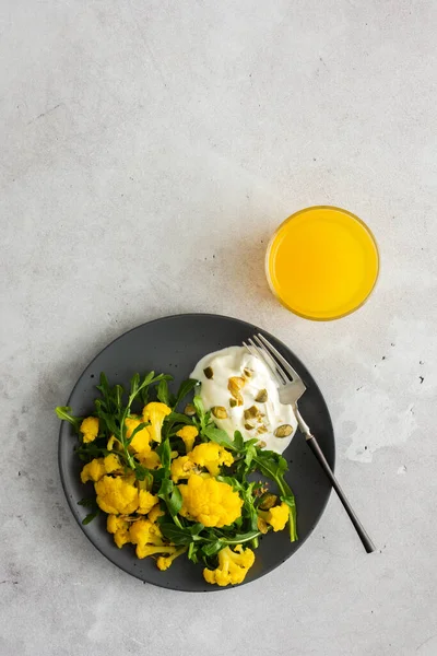 沙律与黄色花椰菜和牛油果 希腊酸奶与南瓜籽和橙汁 清淡健康的早餐 顶部视图 — 图库照片