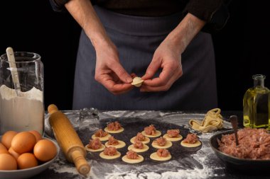 Bir adam geleneksel Rus yemeği köftesi, sütü bir sürahi un, tavuk yumurtası ve kıymalı bir tabak un, sürahi ve zeytinyağında un heykeli yapıyor.