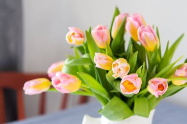 Masadaki sürahide pembe lale buketi, evin içinde çiçekler.