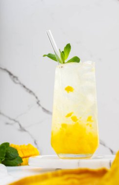 Mango hamuru ve naneli bardakla ferahlatıcı içecek mermer bir duvarın arka planında cam bir kamışla, camın yanındaki mangoyu kes.