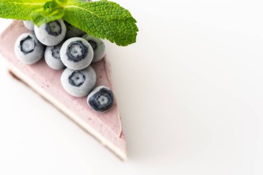 Nane ve donmuş yaban mersiniyle süslenmiş çok renkli lezzetli bir yaban mersinli kek. Beyaz arka planda yakın plan.