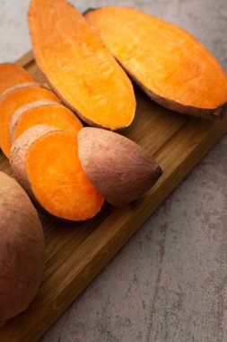 Tam ve çiğ portakallı tatlı patatesi yakın plan kesim tahtasında kes.