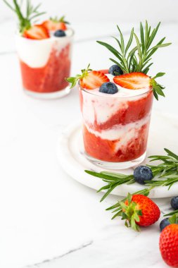 Lezzetli sağlıklı kahvaltı, çilekli smoothie ve doğal yoğurt ve yaban mersini ve biberiye.